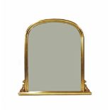 Giltwood arched over mantel mirror, the bevelled glass within a moulded frame with scrolling foliate
