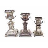 Three similar Continental white metal urns, repousse foliate decorated ,upon stepped square pillar