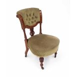 Late Victorian walnut green upholstered nursing chair, the scratch carved and upholstered button-