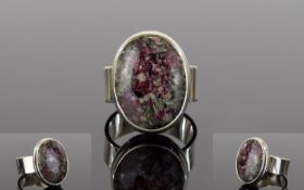 Russian Eudialyte Ring, a 12ct oval cut solitaire eudialyte, bezel set in a silver mount, showing