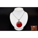 A Red Coral Disc Pendant With Silver Cha
