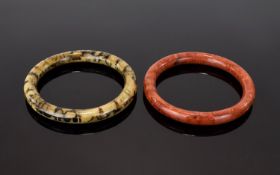 A Pair Of Vintage Agate Bangles Two in total, the first in brick red tone with striated detail.
