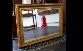 A Large Over Mantle Gilt Mirror with bevelled glass and reeded floral and foliate design to outer