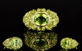 Peridot East/West Cluster Ring, to the centre a bezel set oval cut peridot of a generous 2.