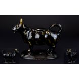 A 19th Century Creamer In the Form Of A Cow Black glazed ceramic cow with gilt hand painted detail
