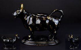 A 19th Century Creamer In the Form Of A Cow Black glazed ceramic cow with gilt hand painted detail