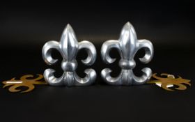 A Pair Of Modern Fire Dogs In white metal and gold tone Fleur De Lys Design. Length 10 inches