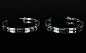 A Pair of DKNY Large Hoop Earrings with the DKNY logo etched to the side of the earrings.