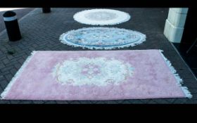 Three Wool Rugs. Two circular wool rugs, one white and pink, one pastel blue and a further pink