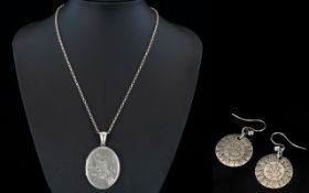 A Large Silver Oval Shaped Hinged Locket with Chased Decoration to Front Panel,