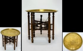 Middle Eastern Occasional Table Engraved circular brass table top on a folding spindle base.