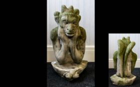 A Reconstituted Stone Figure In The Form Of A Perched Gargoyle Raised on plectrum form scroll base,