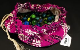 A Collection Of Vintage Glass Marbles Housed in floral printed drawstring pouch, contains various