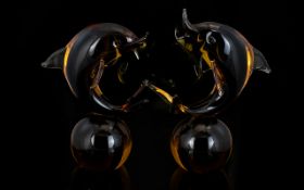 A Pair Of Murano Glass Dolphin Figures Each in amber glass seated on spherical bases,