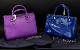 Two Armani Designer Handbags, one in blue and one in purple, both with original dust covers.