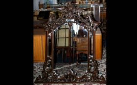 Large Carved Empire Style Mirror housed in carved and moulded dark wood frame with ornate scroll