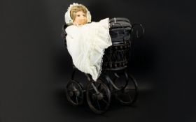 A Miniature Pram And Doll Victorian style pram in black metal with black canvas lining, together