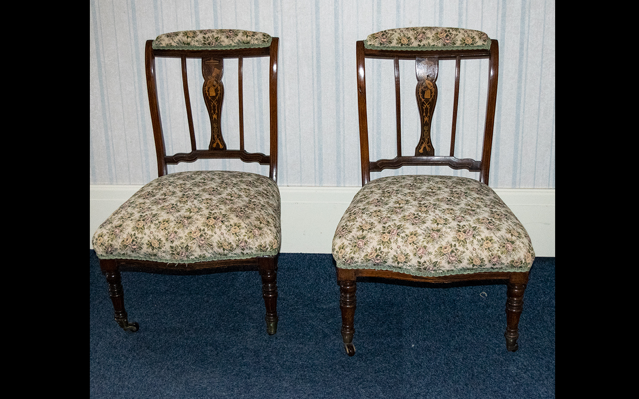 A Pair Of Mahogany Edwardian Salon Chairs. Inlaid slats, turned supports with brass castors.