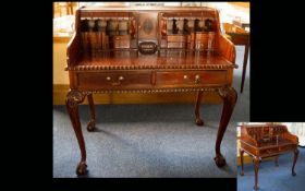 A Mahogany Writing Bureau raised on claw and ball feet with carved apron, two central drawers.