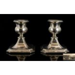 A Pair Of Squat Sterling Silver Candlesticks Of plain form raised on square base,