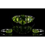 Peridot Three Stone Ring, a 2ct oval cut central peridot, flanked by two trillion cut similar stones