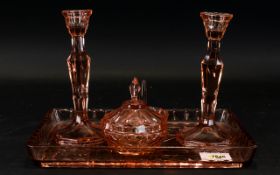 A Pink Coloured Glass Dressing Table set comprising tray, candlesticks, trinket dish and jewelry