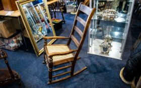 Rocking Chair Of plain form with caned seat and turned stretcher, aged patina throughout.