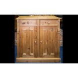A Freestanding Pine Cabinet with panelled pine doors, two drawers on a plinth base,
