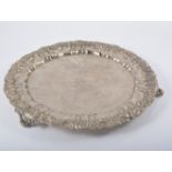 White metal salver, gadrooned wavy rim on three scrolled feet, engraved crest and scrolled field,