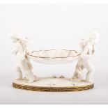 Pair of pottery table centres, each designed with angels supporting a basket, oval plinth,