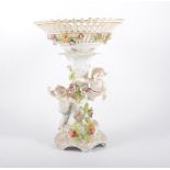 Continental porcelain comport, pierced basket, the column modelled with Cherubs and flowers, 33cm.