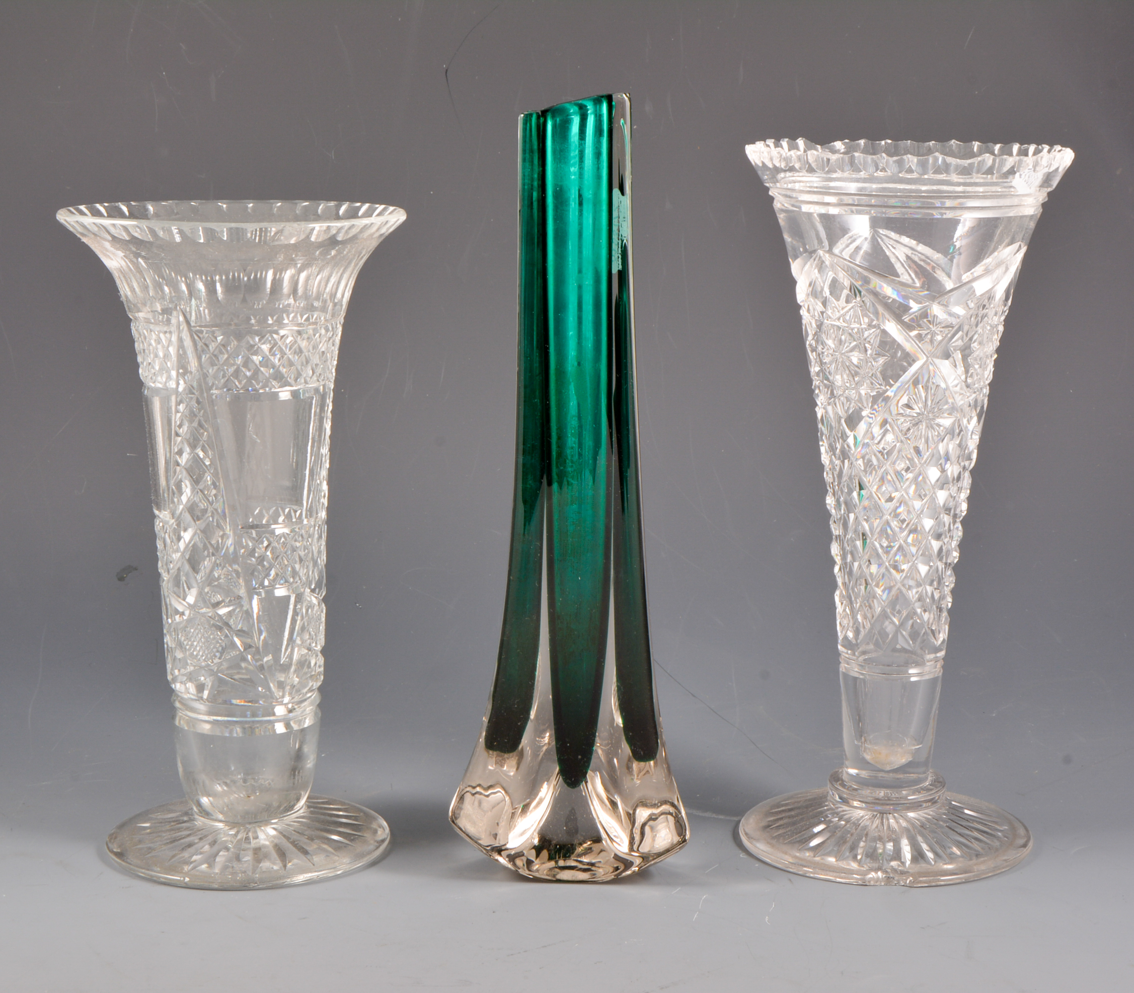 Five crystal vases and a slender green glass vase.