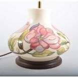 A Moorcroft Table Lamp, "Magnolia" design on a cream ground, 22cm high, squat form on a wooden base.