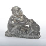 Inuit stone carving of a hunter with bag, 14cm wide.