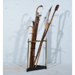A brass triangular stick stand with thirteen homemade sticks, mostly with horn and antler tops,