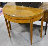 A walnut veneer demi-lune card table, supported on square tapered legs with a plate glass top,