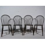 Four stained wood stick back kitchen chairs.