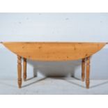 Pine kitchen table drop leaf table, oval top on turned supports, length 180cm,