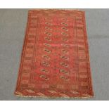 Persian rug, red field with Tekke guls, two rows of eleven guls, enclosed by borders, 174 x 104cm.