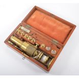 An antique brass field microscope in a fitted mahogany case, rack focusing, six objectives,