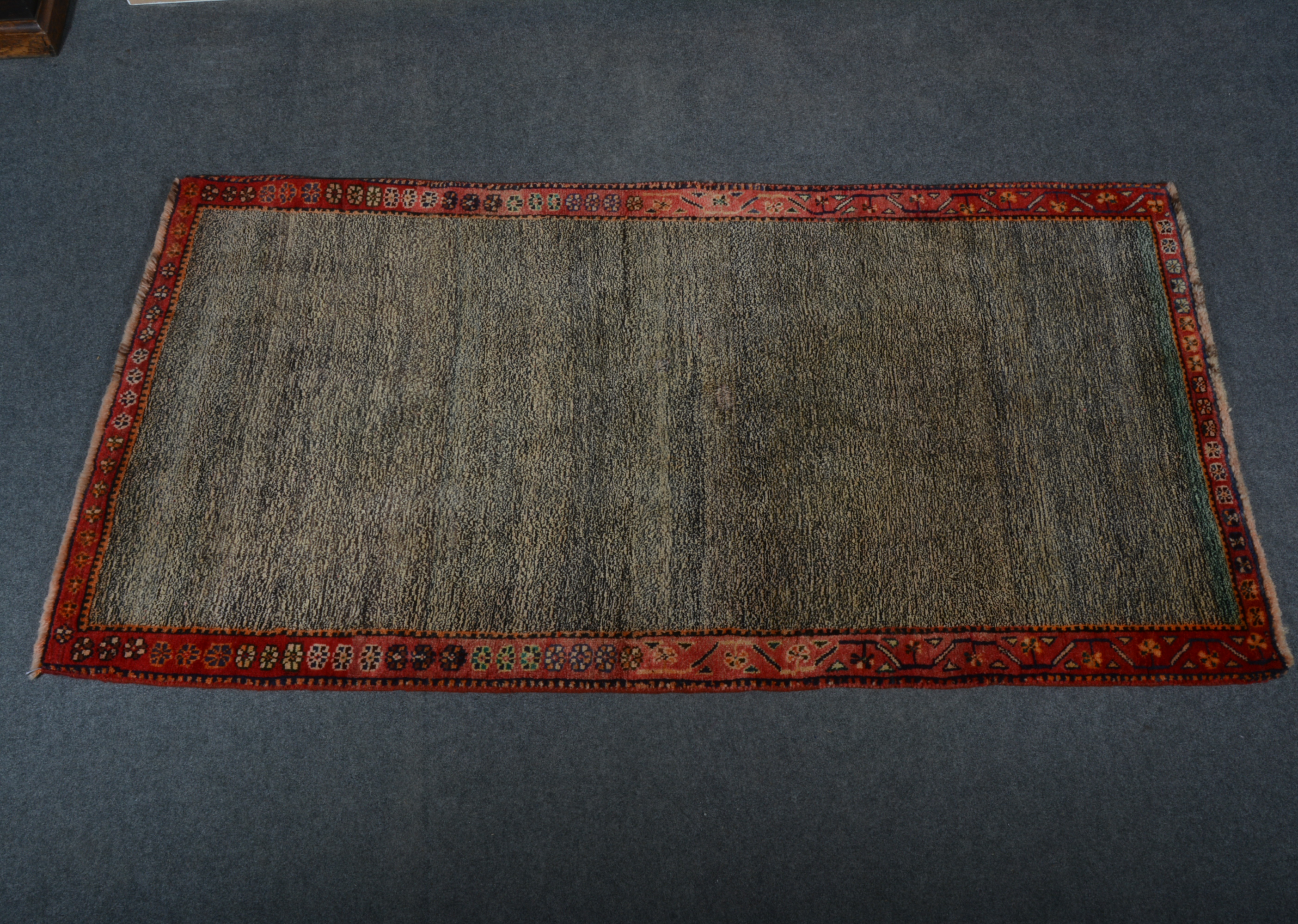 Gabbeh wool rug; a speckled field, enclosed by red borders with boteh floral emblems, 202 x 107cm.