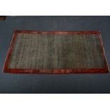 Gabbeh wool rug; a speckled field, enclosed by red borders with boteh floral emblems, 202 x 107cm.