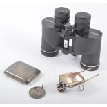 Silver cigarette case, silver medal, white metal miniature wheelbarrow, and a pair of binoculars.