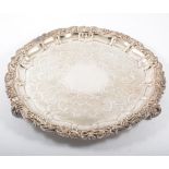 A silver plated salver, floral engraved base with a raised scrolling border on three cast feet,