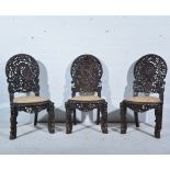 Three Burmese carved hardwood side chairs, cartouche panel backs,