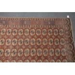 Afghan Tekke rug, rows of tiles on a red ground within borders, 238cm x 173cm.