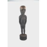 Oceanic carved wood standing figure, elongated torso with flattened arms held to dies,