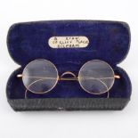 A pair of yellow metal rimmed spectacles,