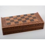 A carved wooden chess set in case with chequered board top, another carved wooden chess board.