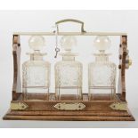 Edwardian oak tantalus, silver plated mounts, three cut glass decanters, 39cm.